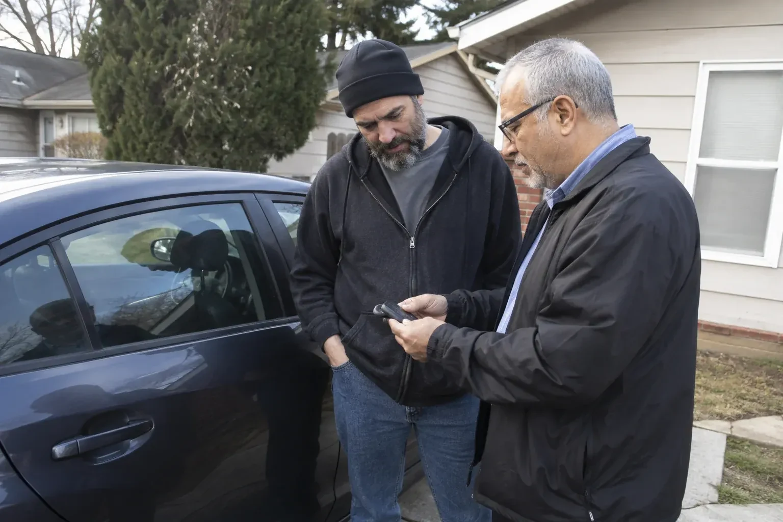 Two adults discussing a key fob beside a parked car. — Car Lockout Service, Markham